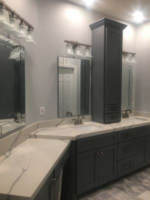 Modern bathroom vanity with dark cabinets, large mirrors, marble countertop, and built-in lighting
