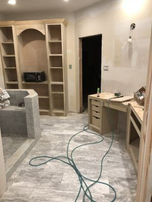 Partially renovated room with built-in shelves, desk, couch, and tools on the floor