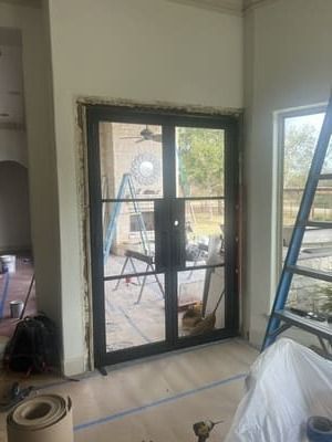 Interior room with black-framed glass door, ladder, and construction materials during renovation