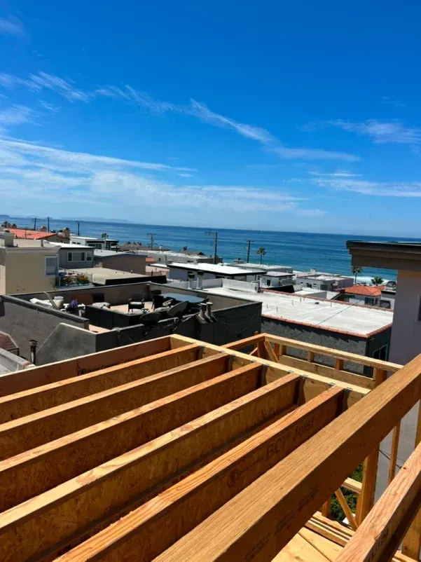 Wooden construction framing with a view of the ocean under a blue sky.