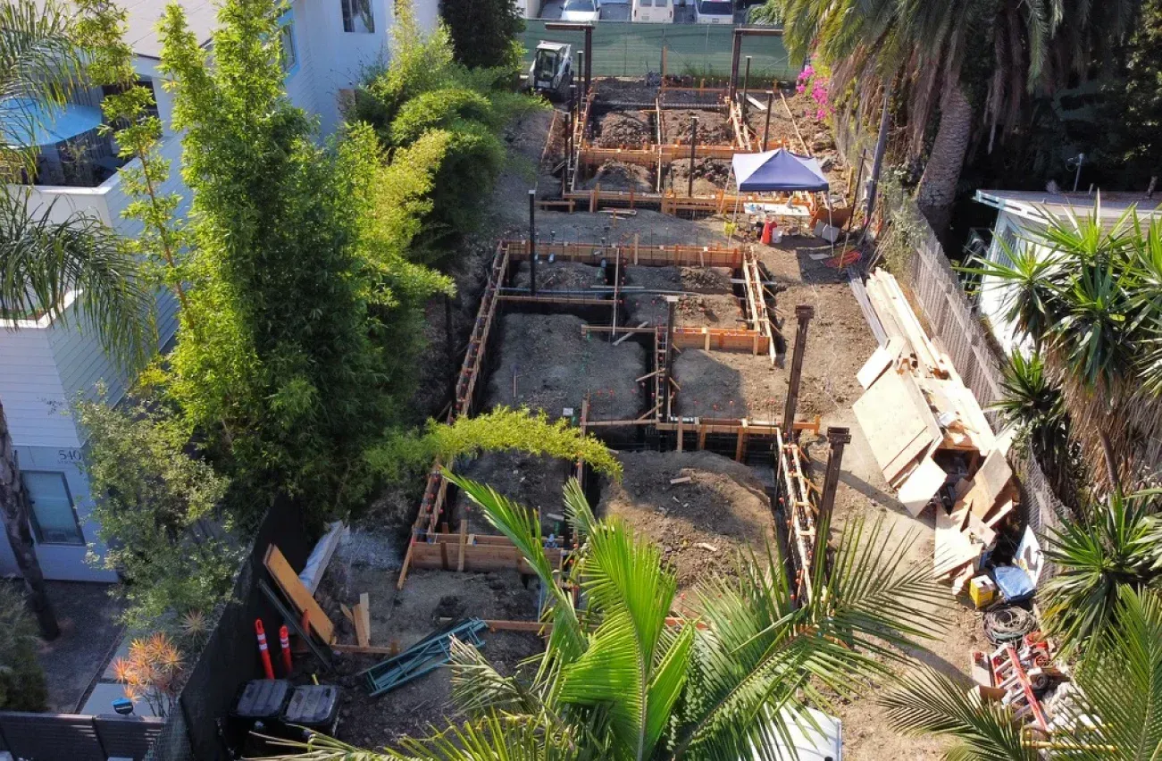 Construction site: Wooden framing for a building in a residential area, with equipment and debris.