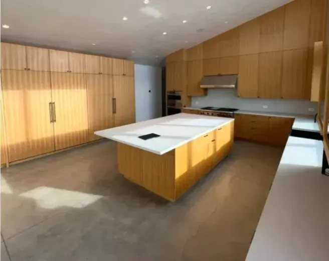 Modern kitchen with light wood cabinets and large island. Concrete floors, natural light.