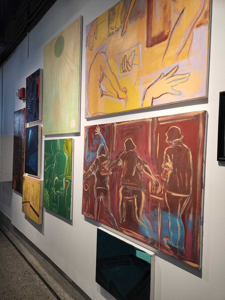 Colorful abstract paintings arranged in a gallery-style display on a wall.
