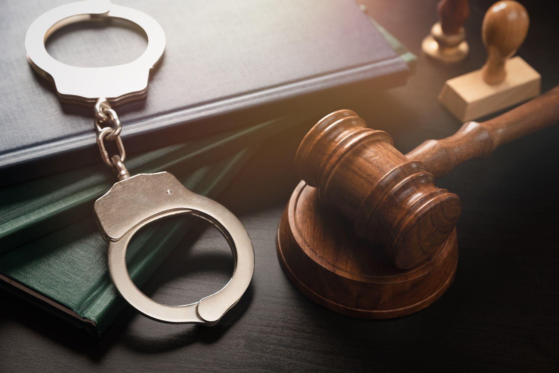 Handcuffs, gavel, and law books on a dark surface, suggesting a legal or judicial context.