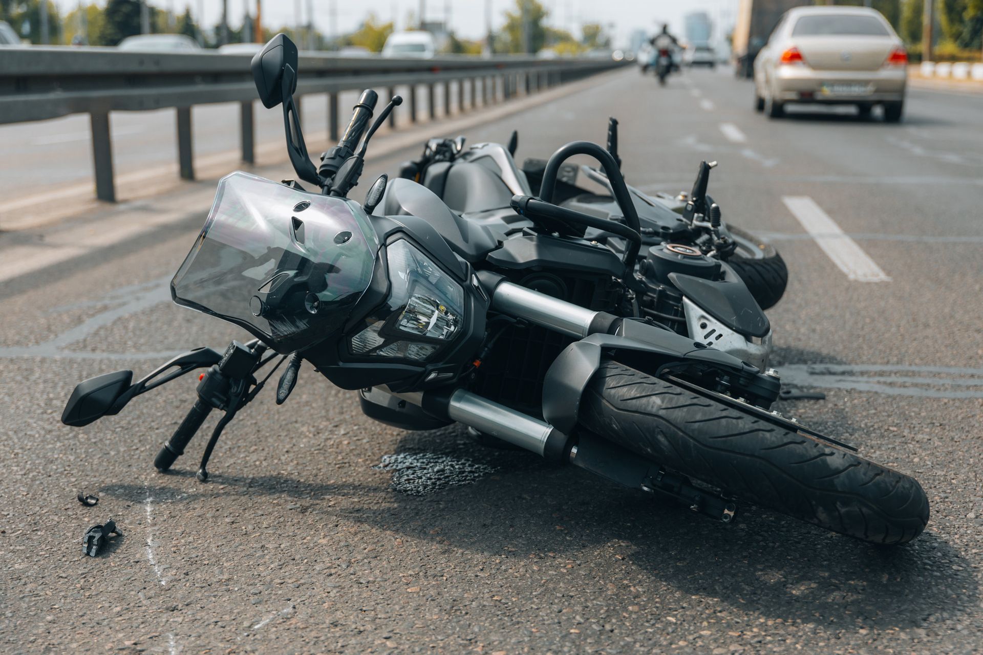 Motorcycle crashed on a road, lying on its side after an accident.