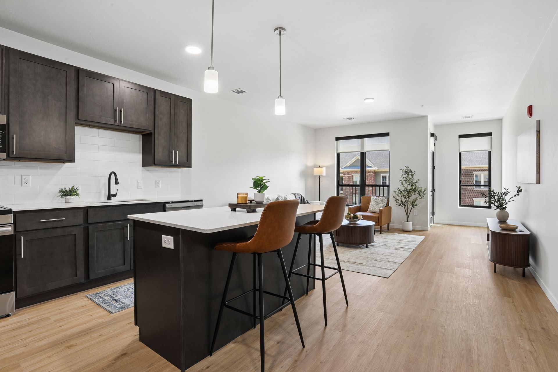 Modern open kitchen and dining area with dark cabinets, island seating, and light wood floors