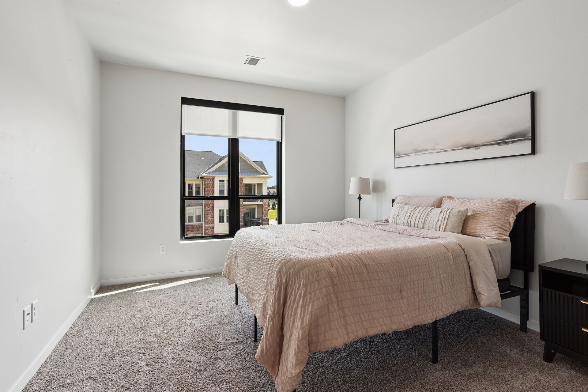 Bright bedroom with a bed, window, carpeted floor, and neutral decor