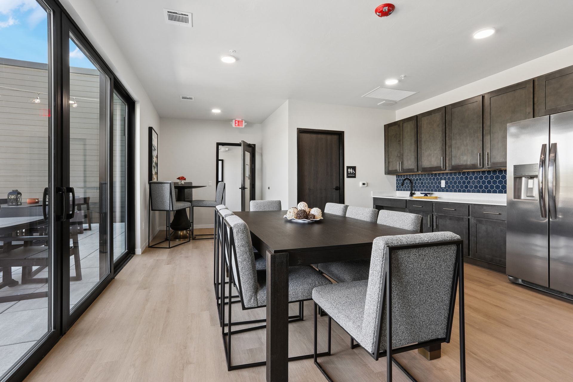 Modern kitchen and dining area with dark cabinets, island seating, and sliding glass doors to a patio.