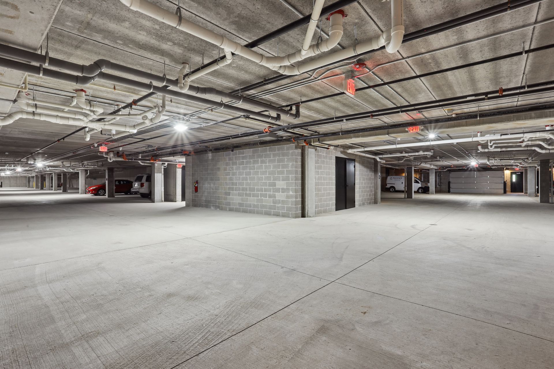 Empty concrete parking garage with exposed ceiling pipes and columns