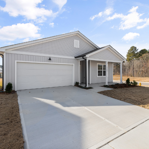 Gray house with a garage and driveway, under a blue sky.