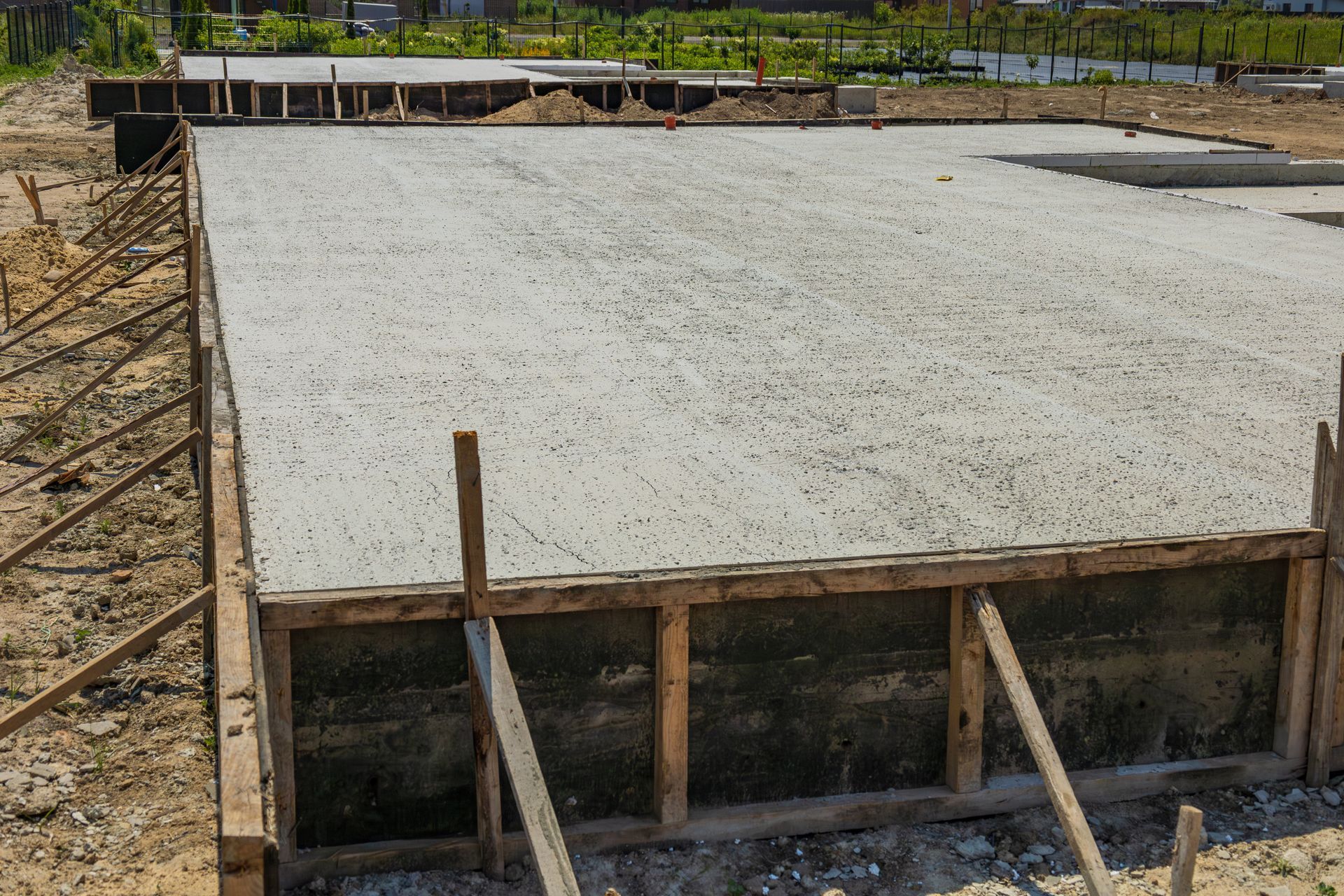 Concrete foundation for a building, gray with wooden frame in an outdoor setting.