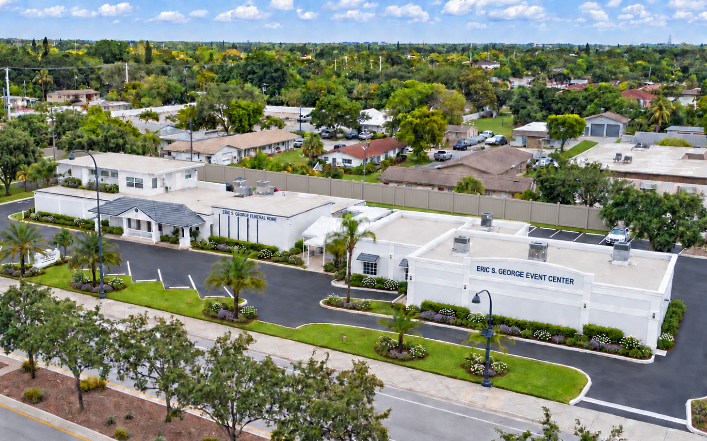 Aerial view of white apartment buildings along a tree-lined street in a suburban neighborhood.