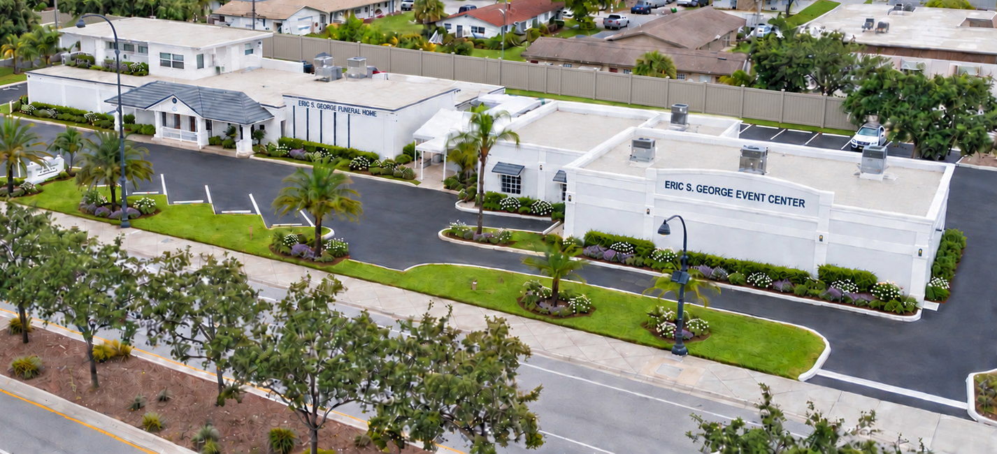 Aerial view of white apartment buildings along a tree-lined street in a suburban neighborhood.