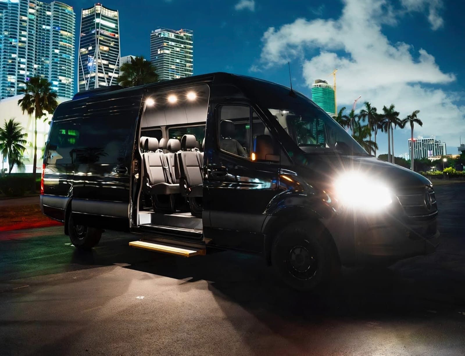 Black van with open sliding door and lit interior parked on a city street at night