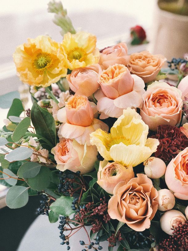 Pastel bouquet of yellow, peach, and cream roses with greenery