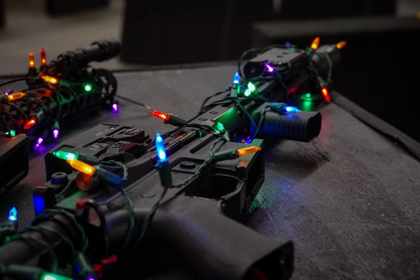 Black rifle wrapped in colorful Christmas lights.