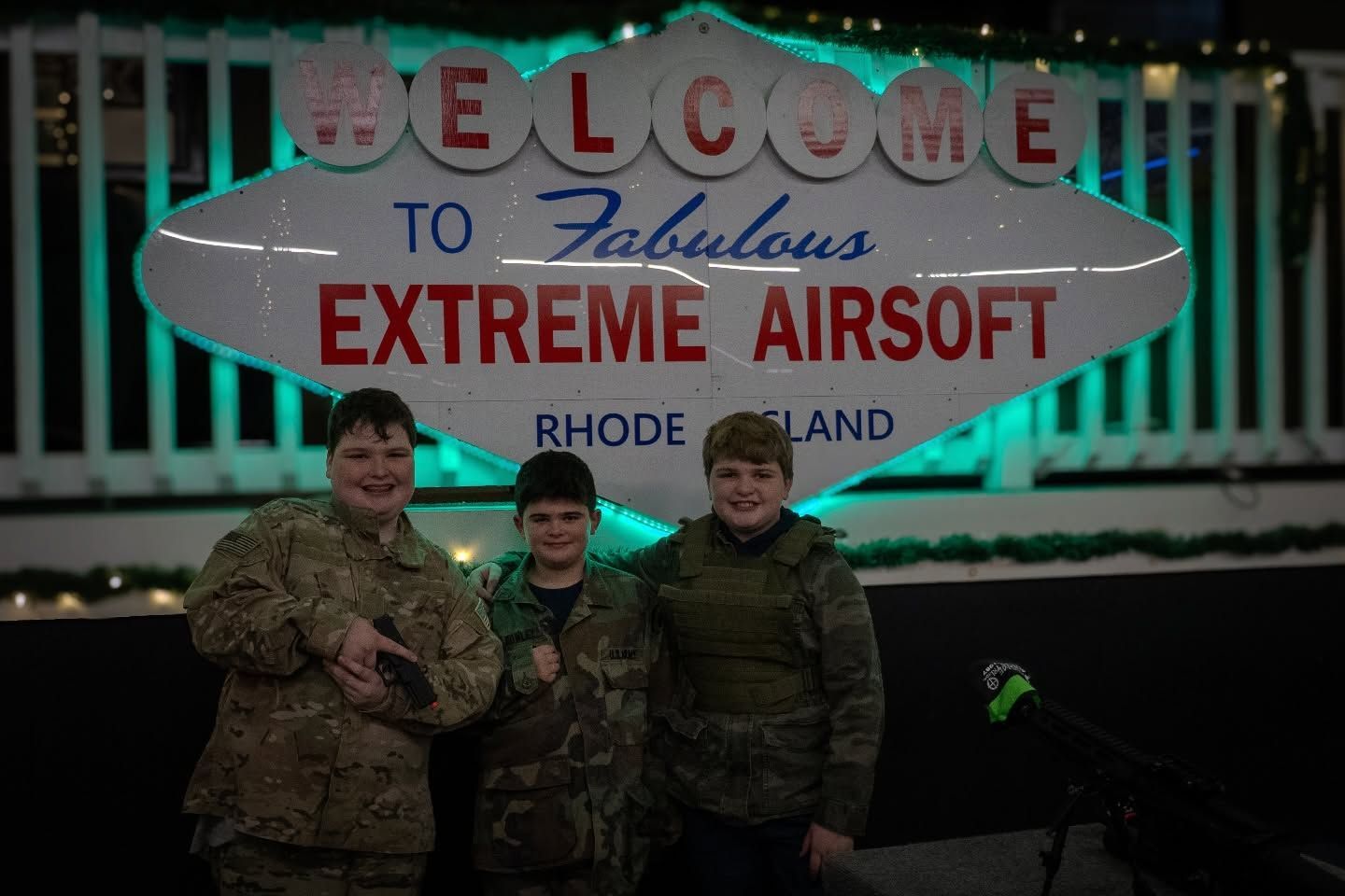 Three people in tactical gear stand in front of a 