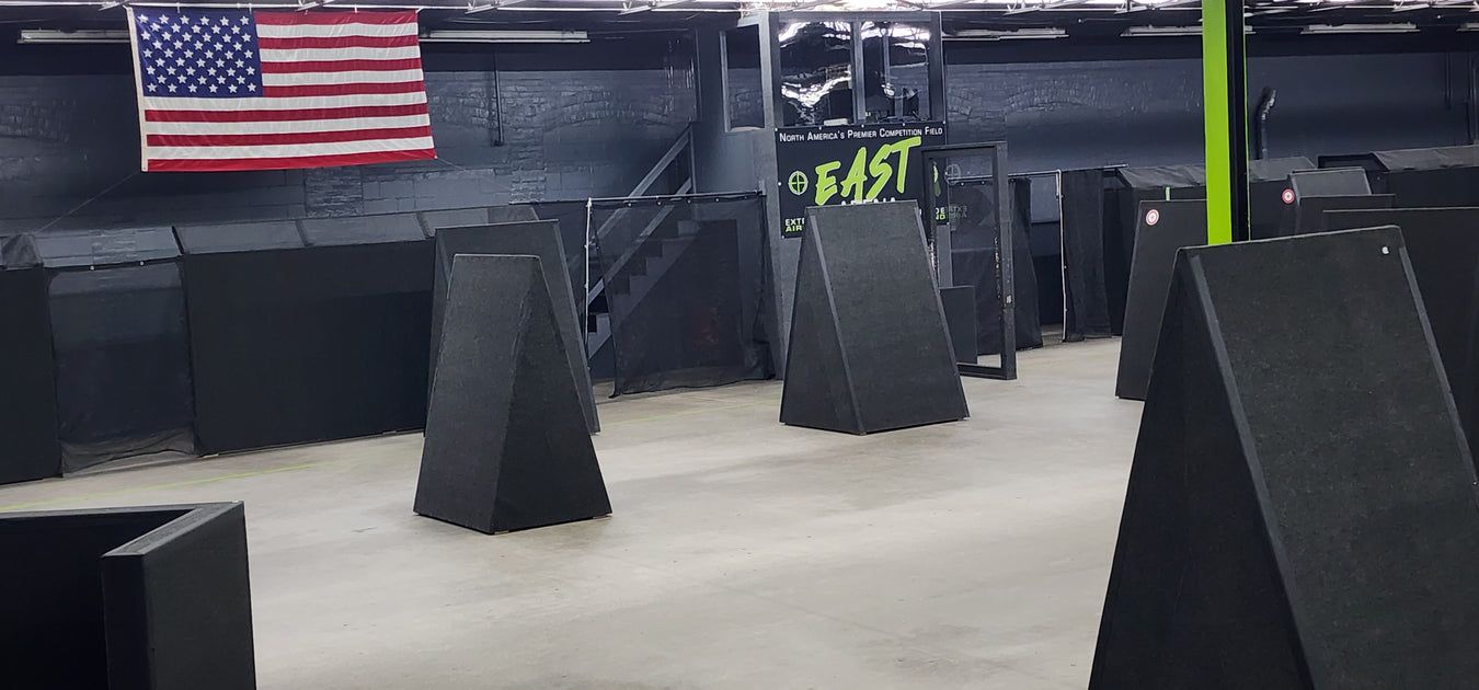 Interior of a laser tag arena with black obstacles, American flag on the wall.
