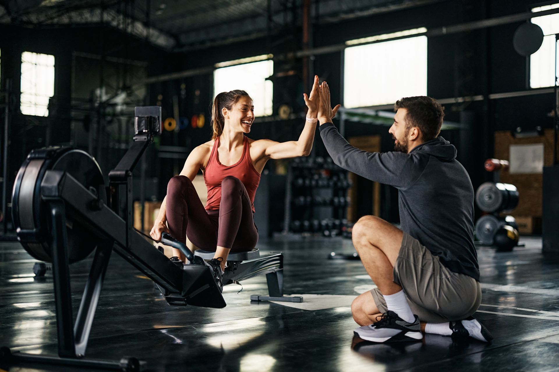 A man and a woman are giving each other a high five in a gym.