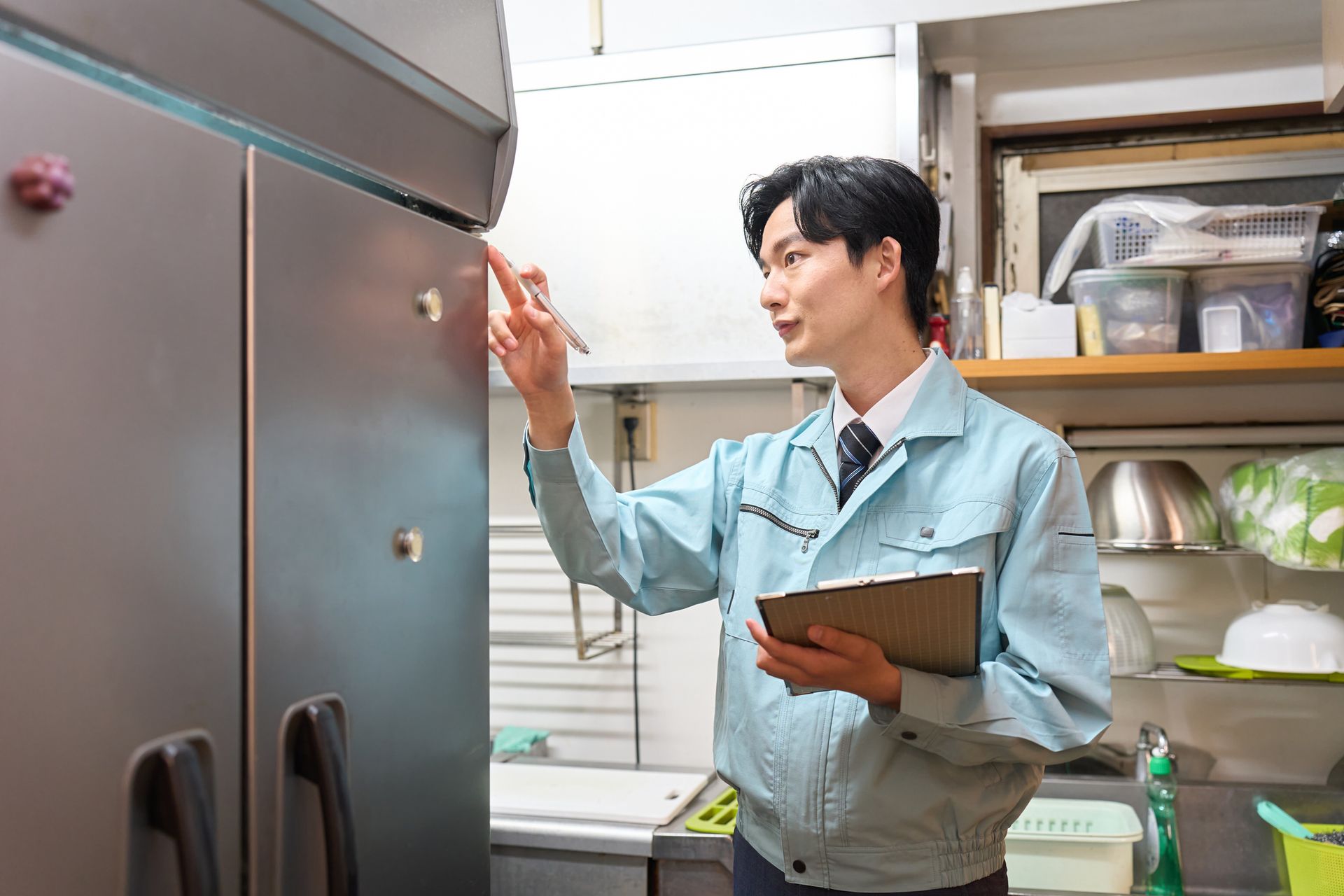 A man is checking a restaurant's refrigerator.