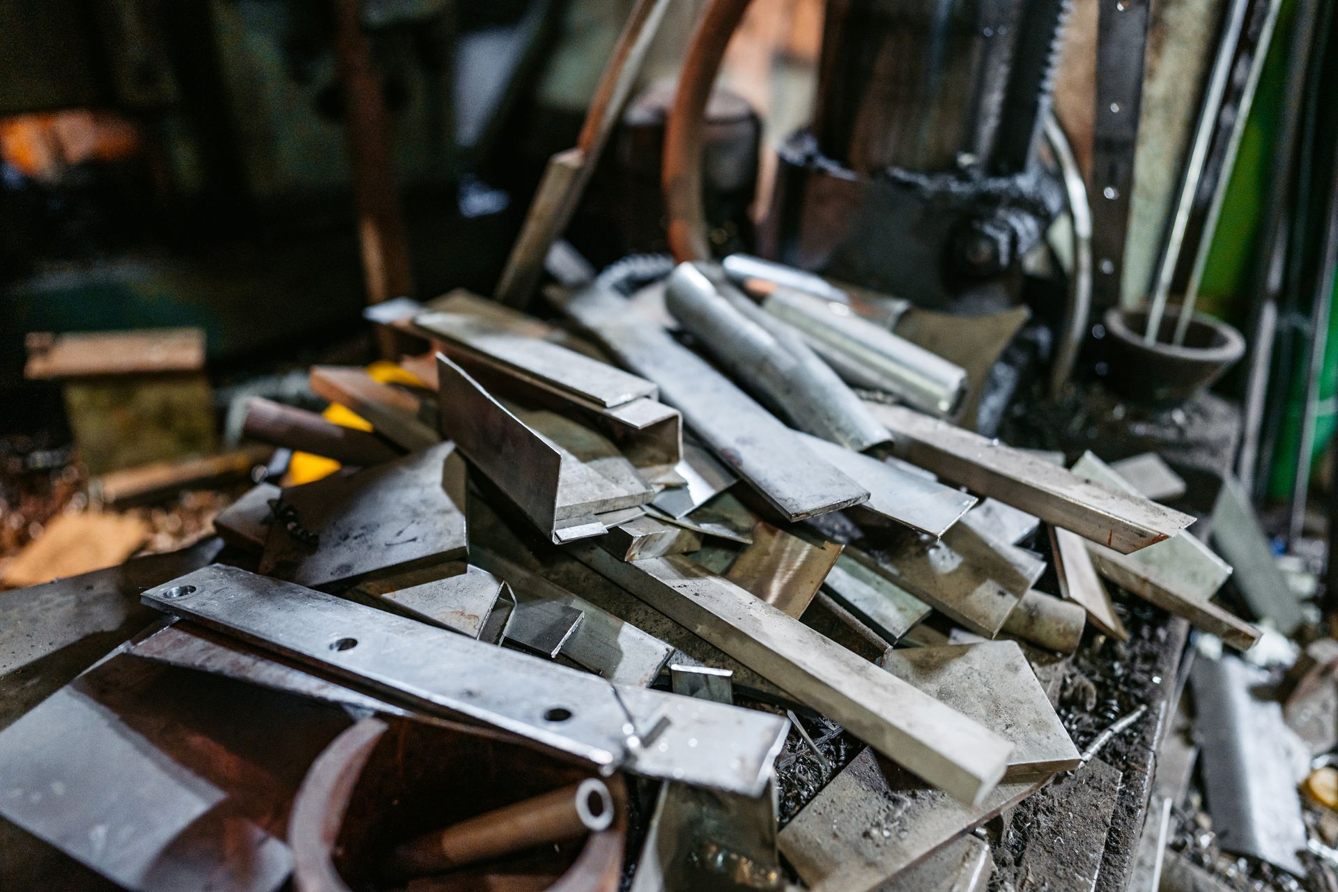 Scrap metal dealers sorting steel offcuts on workshop table with industrial machinery behind.