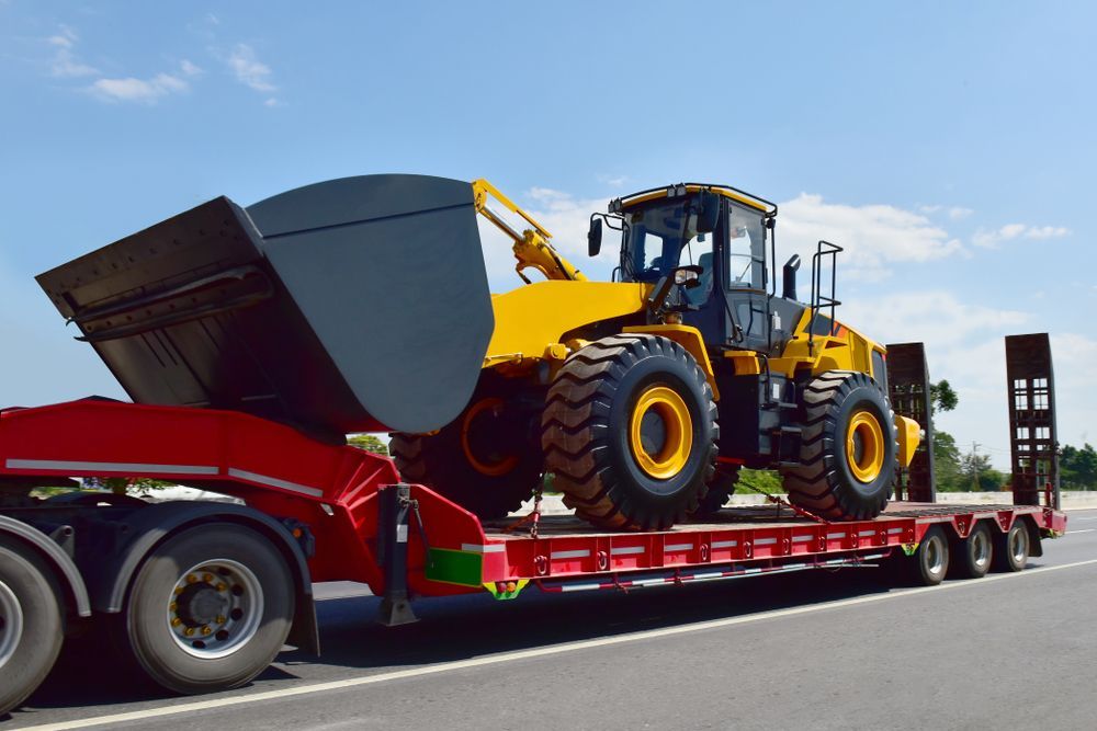 Yellow Earthmover on A Red Flatbed Trailer — Hannant Plant Hire in Perth, WA