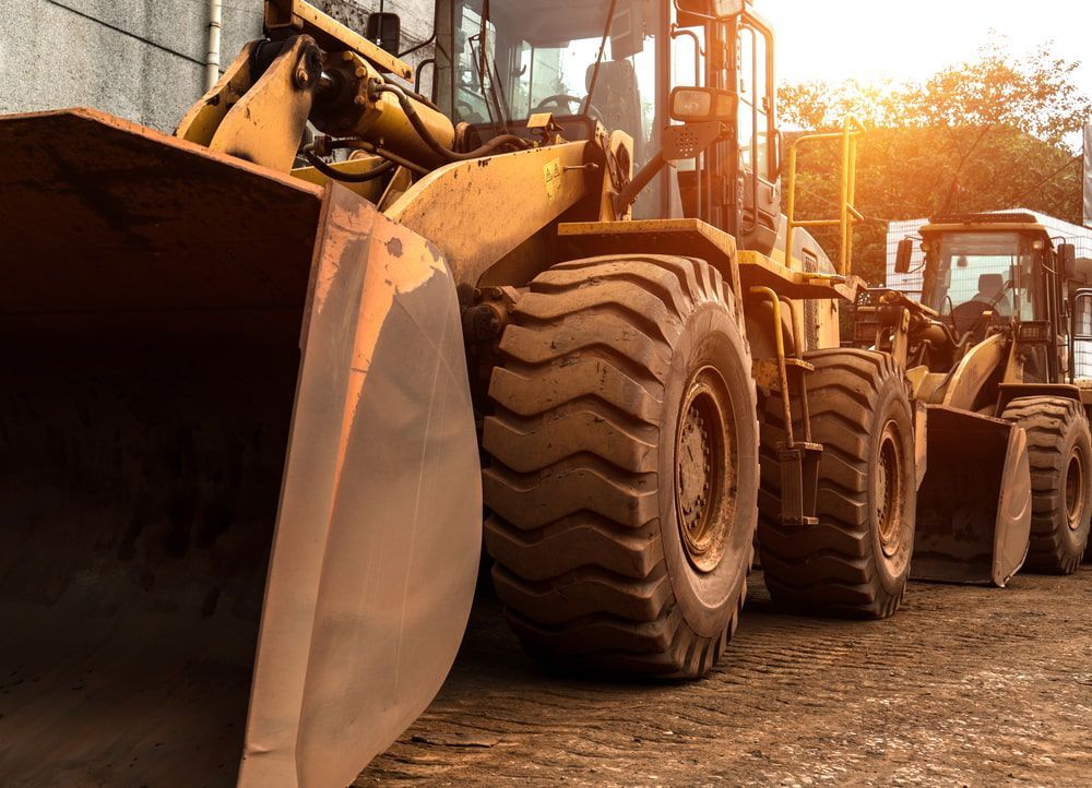 Construction equipment, yellow loaders lined up at a worksite, sunlight. — Hannant Plant Hire in Perth, WA