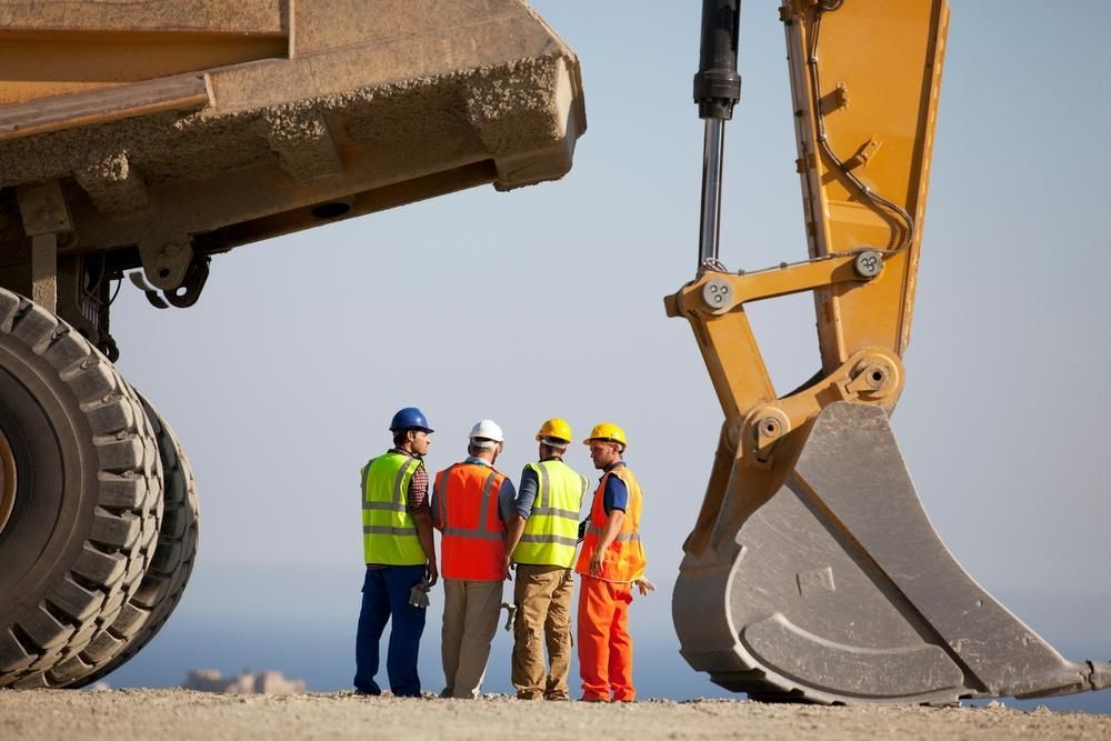 Group of Construction Workers Are Standing in Front of a Large Dump Truck — Hannant Plant Hire in Perth, WA