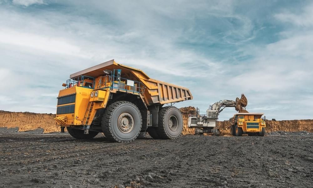 Large Yellow Dump Truck is Driving Through a Dirt Field — Hannant Plant Hire in Robina, QLD