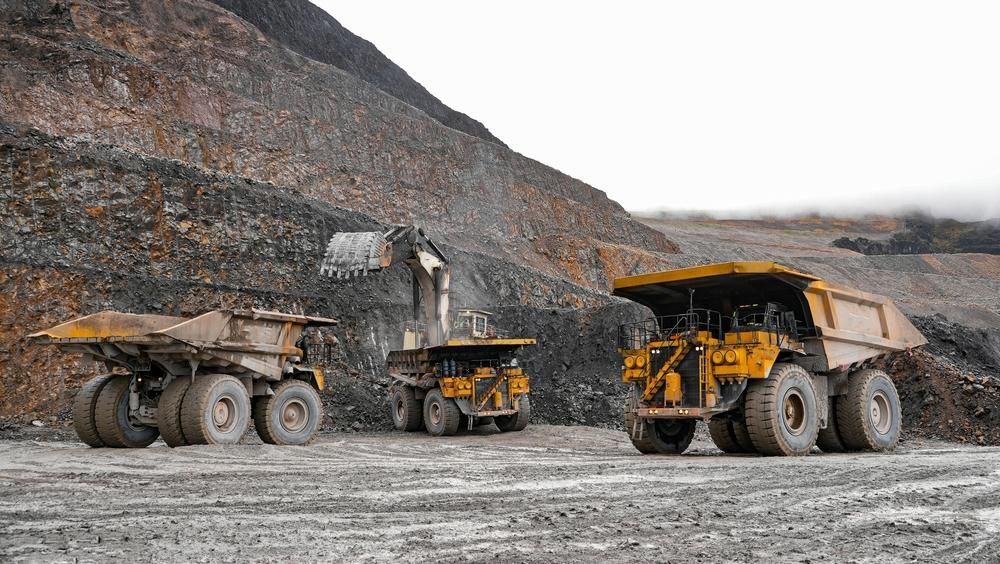 Three Dump Trucks Are Parked in a Dirt Field in a Mine — Hannant Plant Hire in Robina, QLD