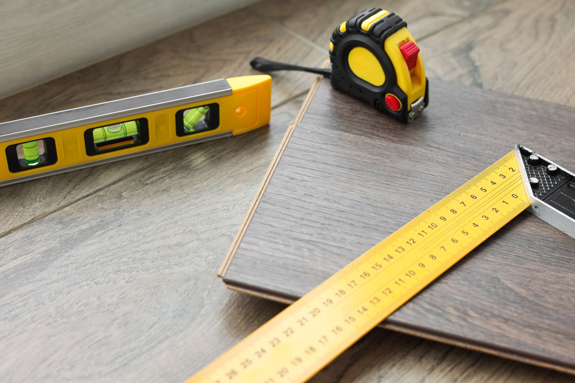Tools on a wood plank: a level, tape measure, and ruler.