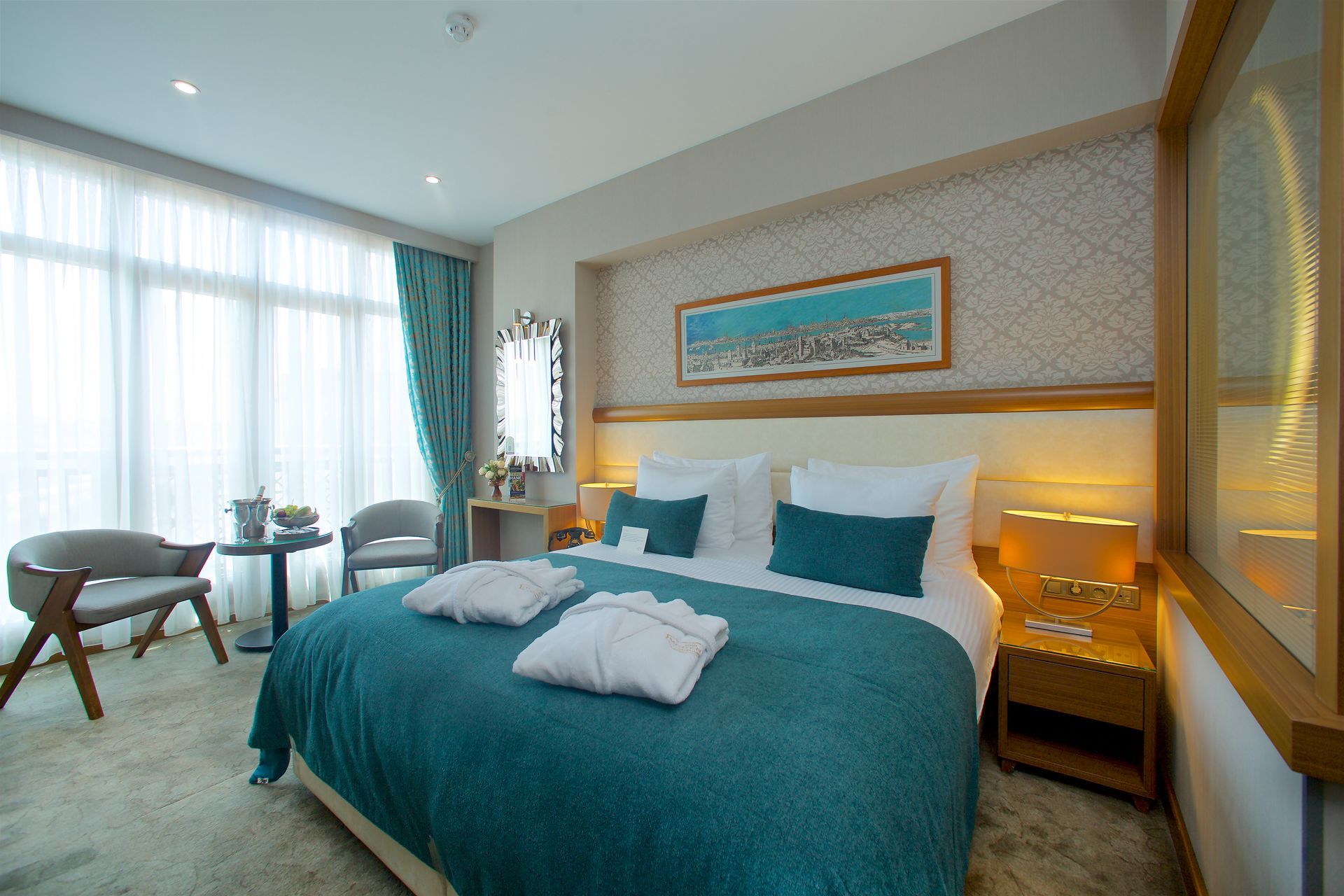 A hotel room with a large bed , chairs and a table.