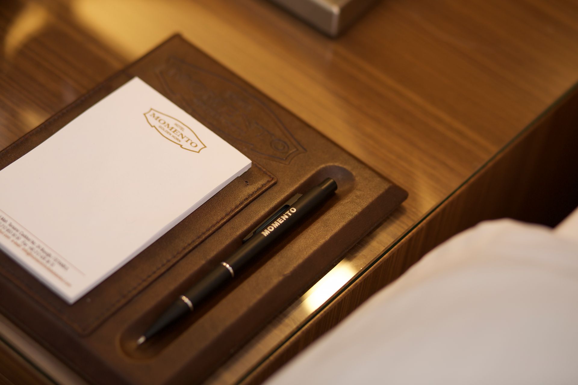 A pen is sitting on a wooden tray next to a notepad