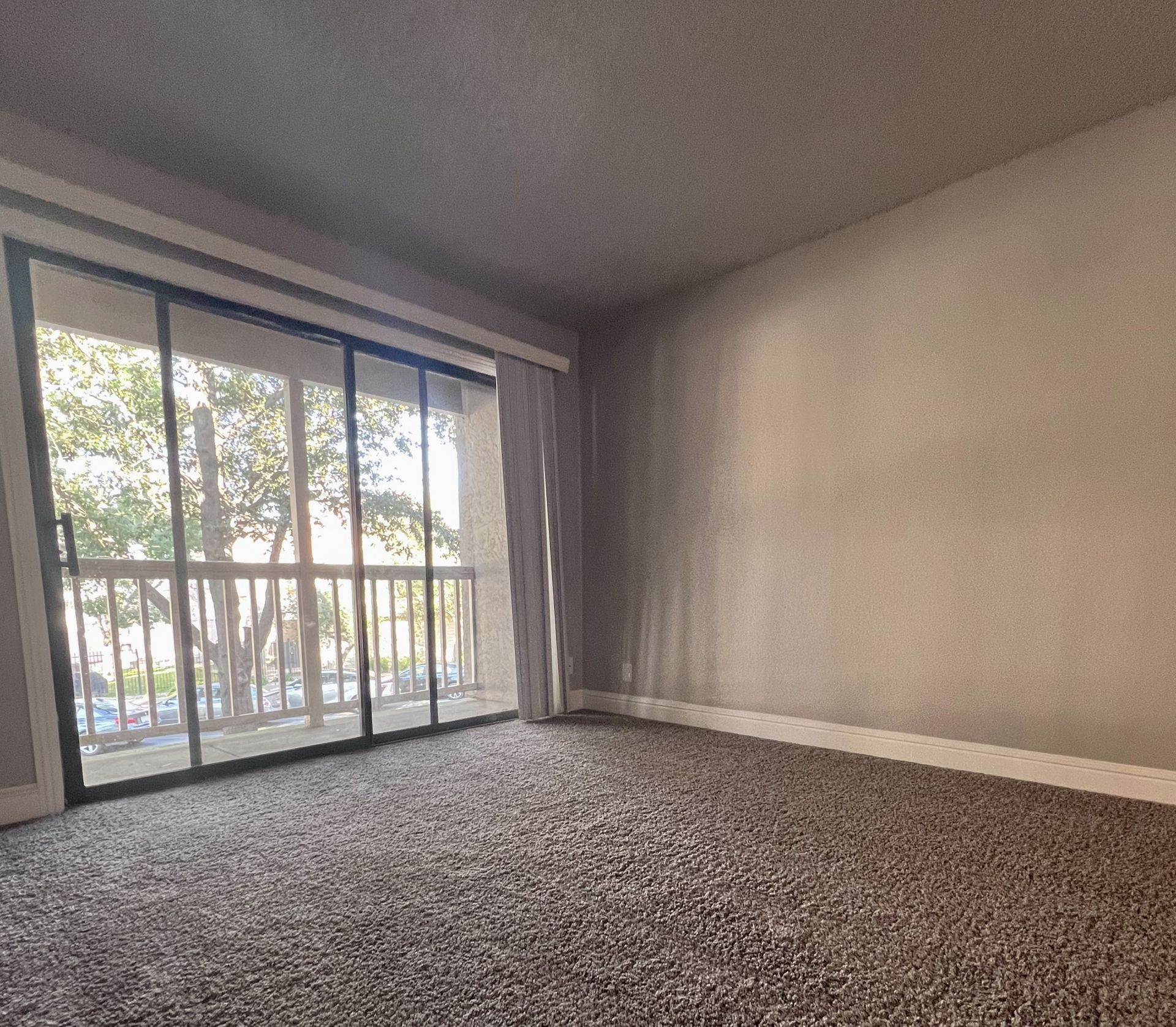an empty room with a balcony and sliding glass doors