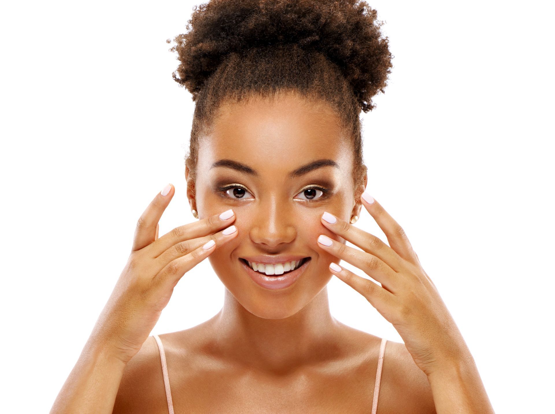 A person smiling, gently touching the skin under their eyes with their fingertips against a white background.