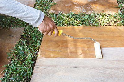 Rolling natural finish sealer onto sandstone surface.