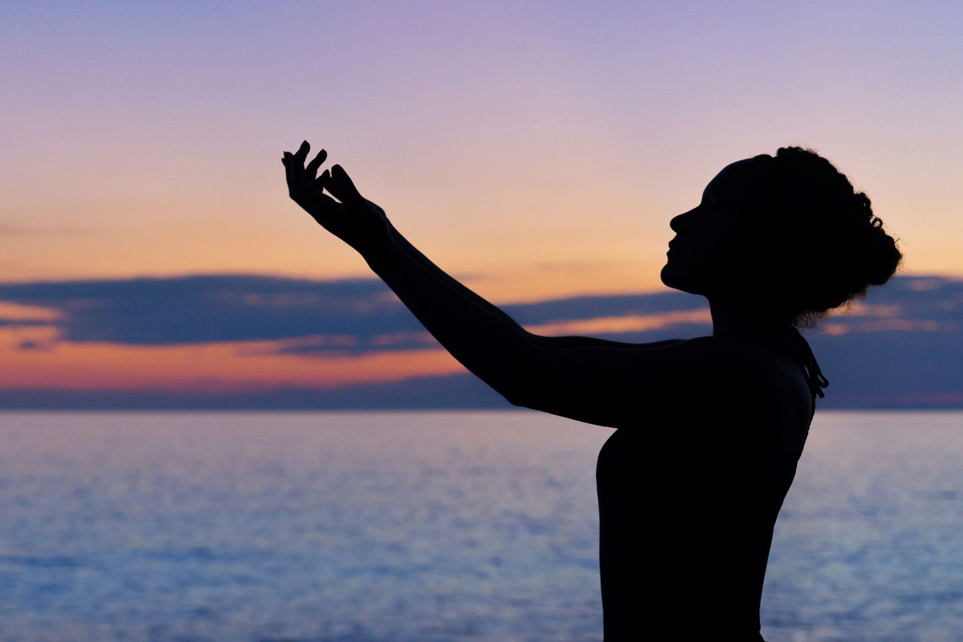 A silhouette of a woman standing in front of the ocean