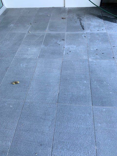 A Close Up of a Tiled Floor With a Leaf on It — The Tile & Stone Specialists in Peregian Beach, QLD