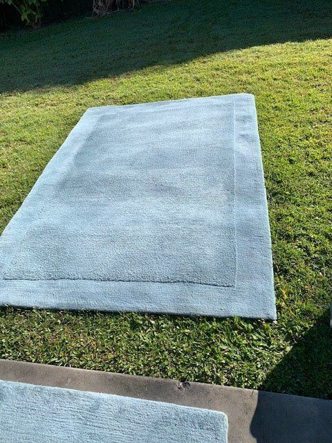 A Large Rug is Sitting on Top of a Lush Green Field — The Tile & Stone Specialists in Peregian Beach, QLD