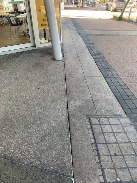 A Concrete Sidewalk Next to a Building With a Brick Curb — The Tile & Stone Specialists in Peregian Beach, QLD