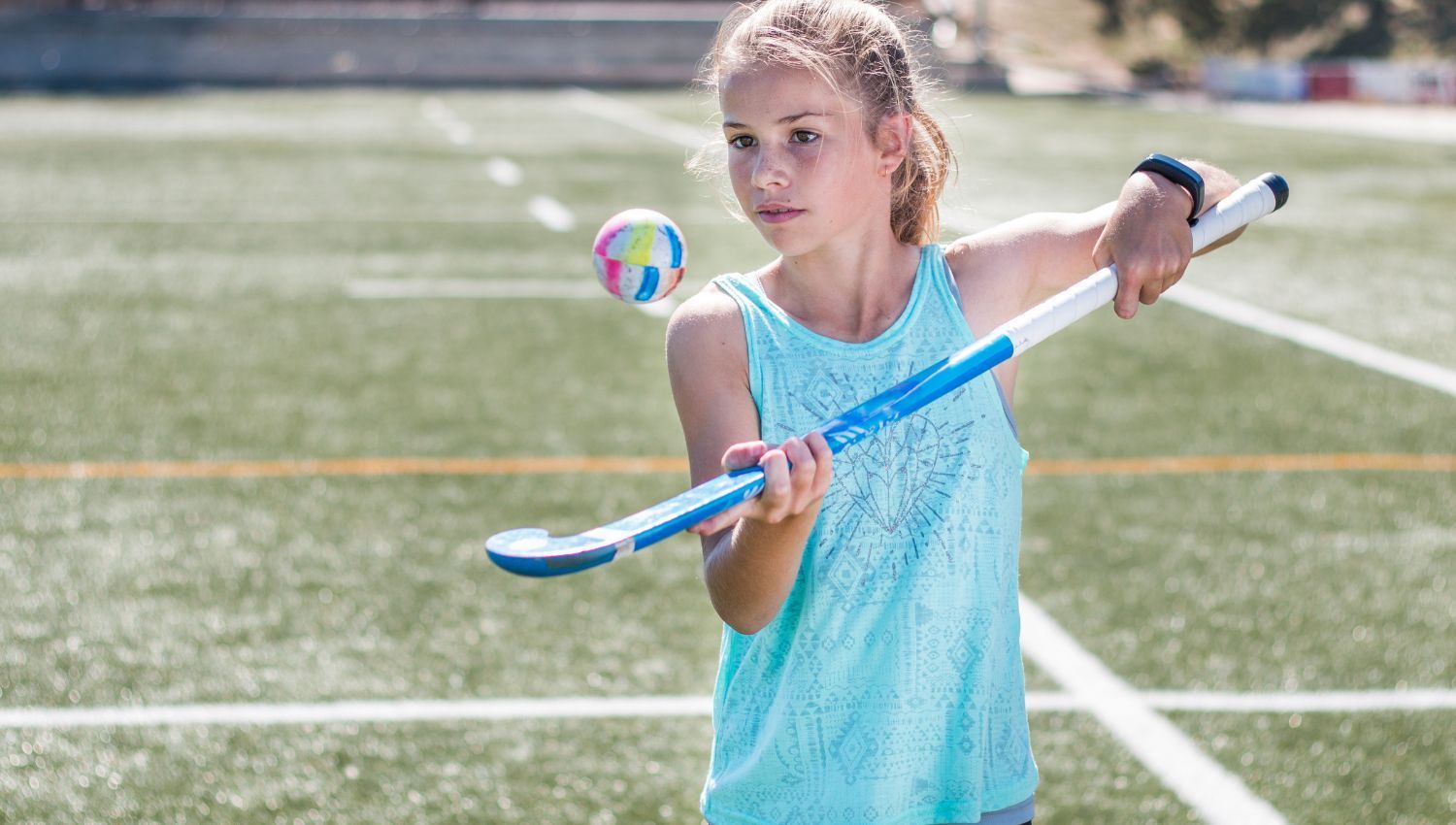 A young girl is playing field hockey on a field.