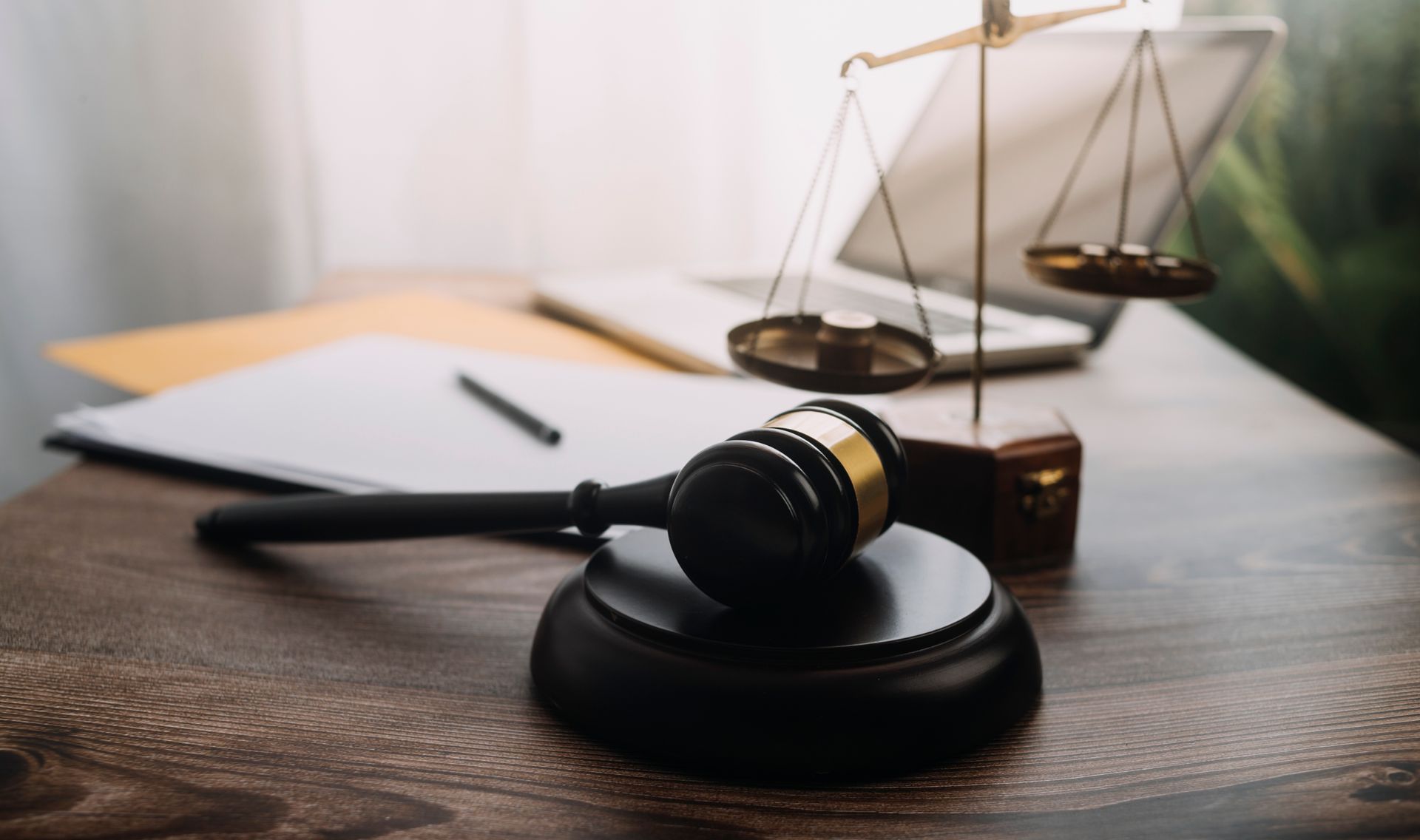 A judge 's gavel and scales of justice are on a wooden table.
