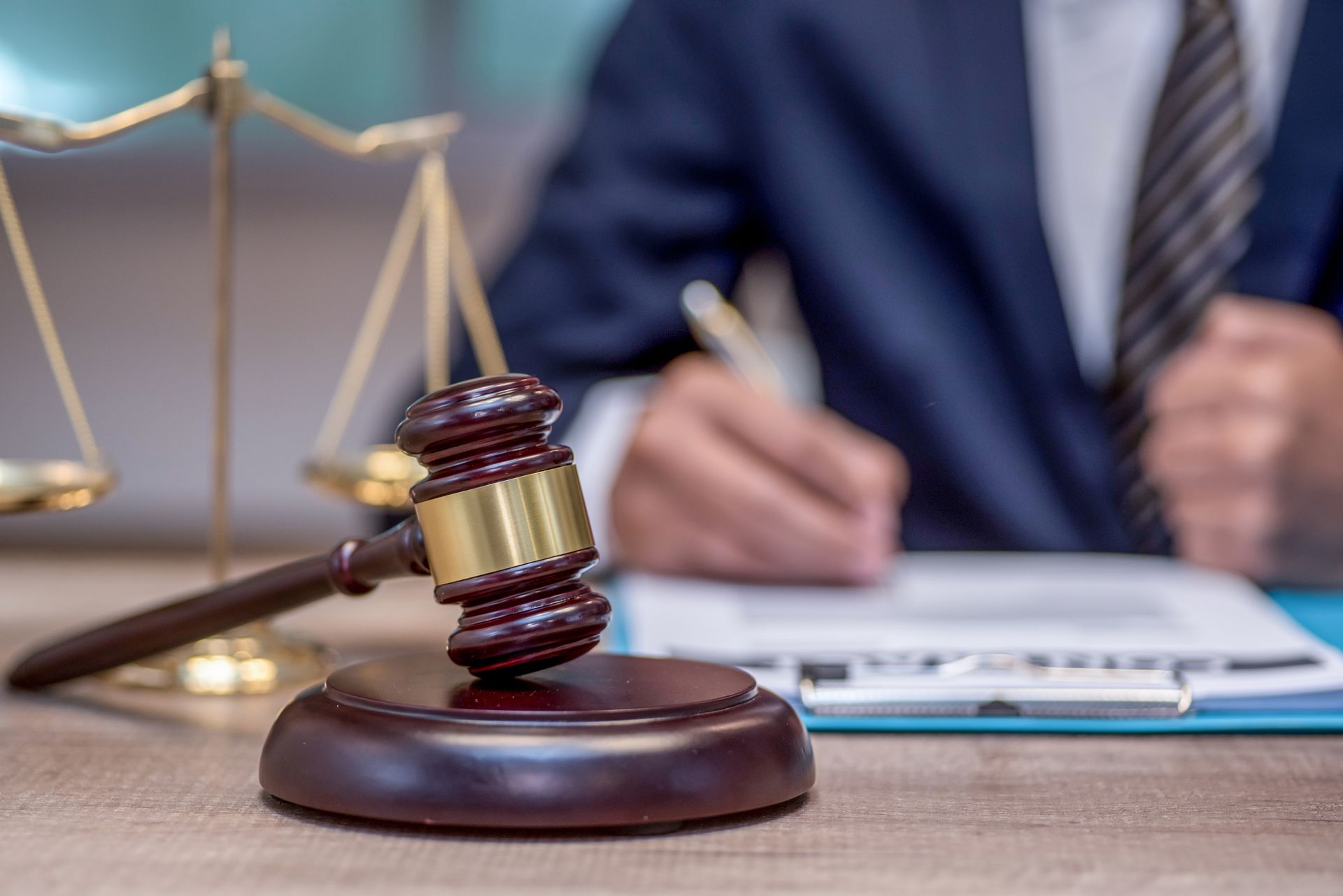 A judge is writing on a clipboard next to a wooden gavel.