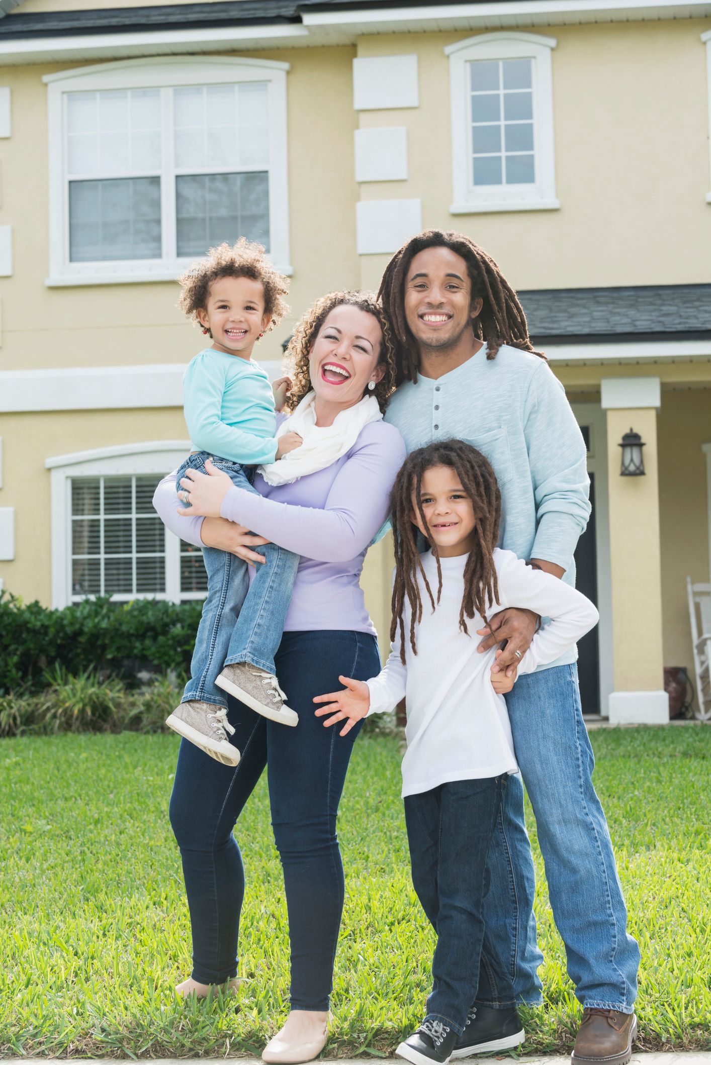 A family is posing for a picture in front of their new house.