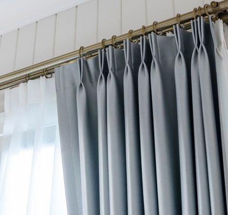 Close-up of Grey, Pleated Curtains Hanging From a Gold Rod — GV Blinds in Shepparton, VIC