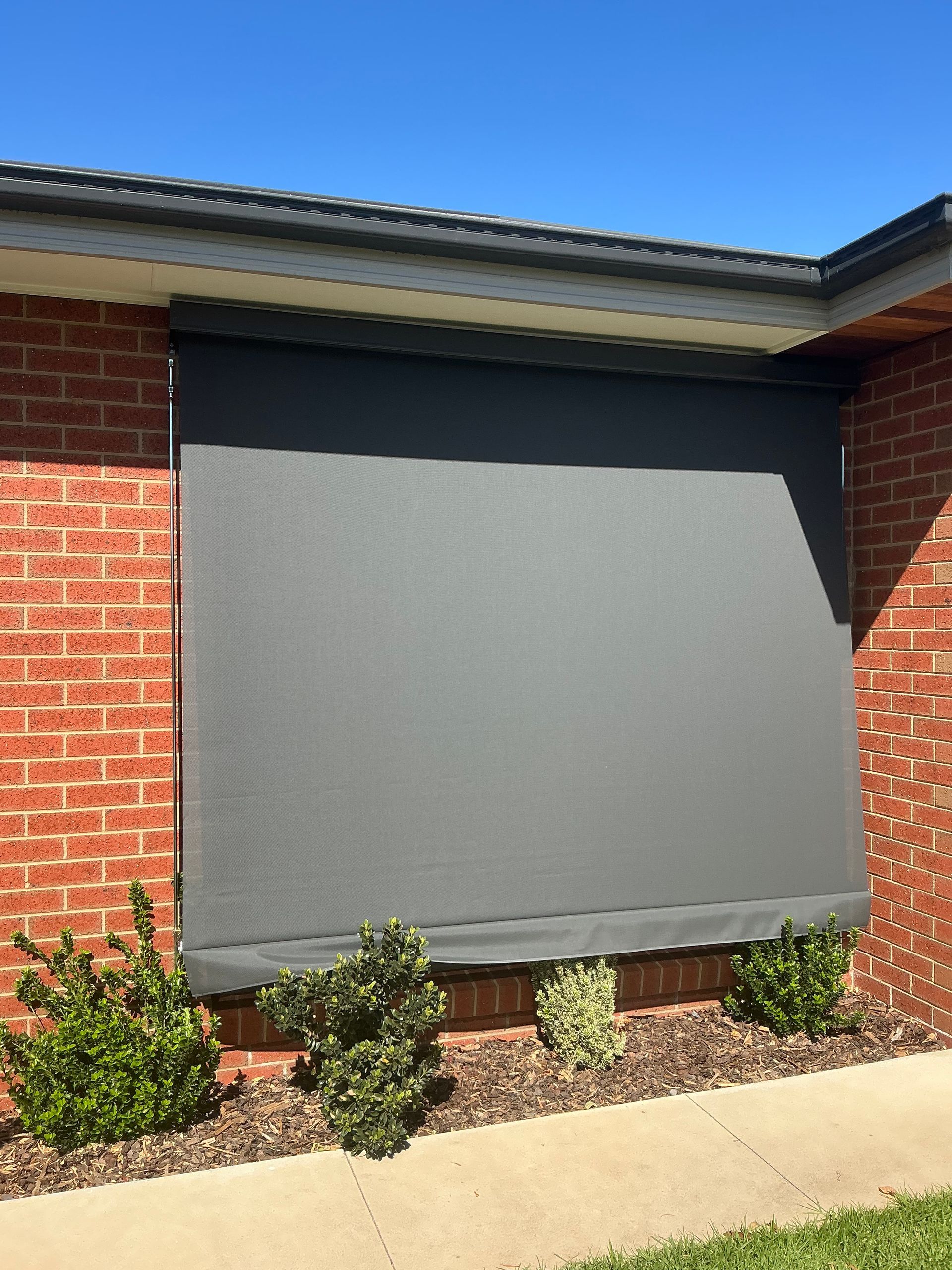 Black Awning Shading Sunlight with Trees and Blue Sky — GV Blinds in Shepparton, VIC