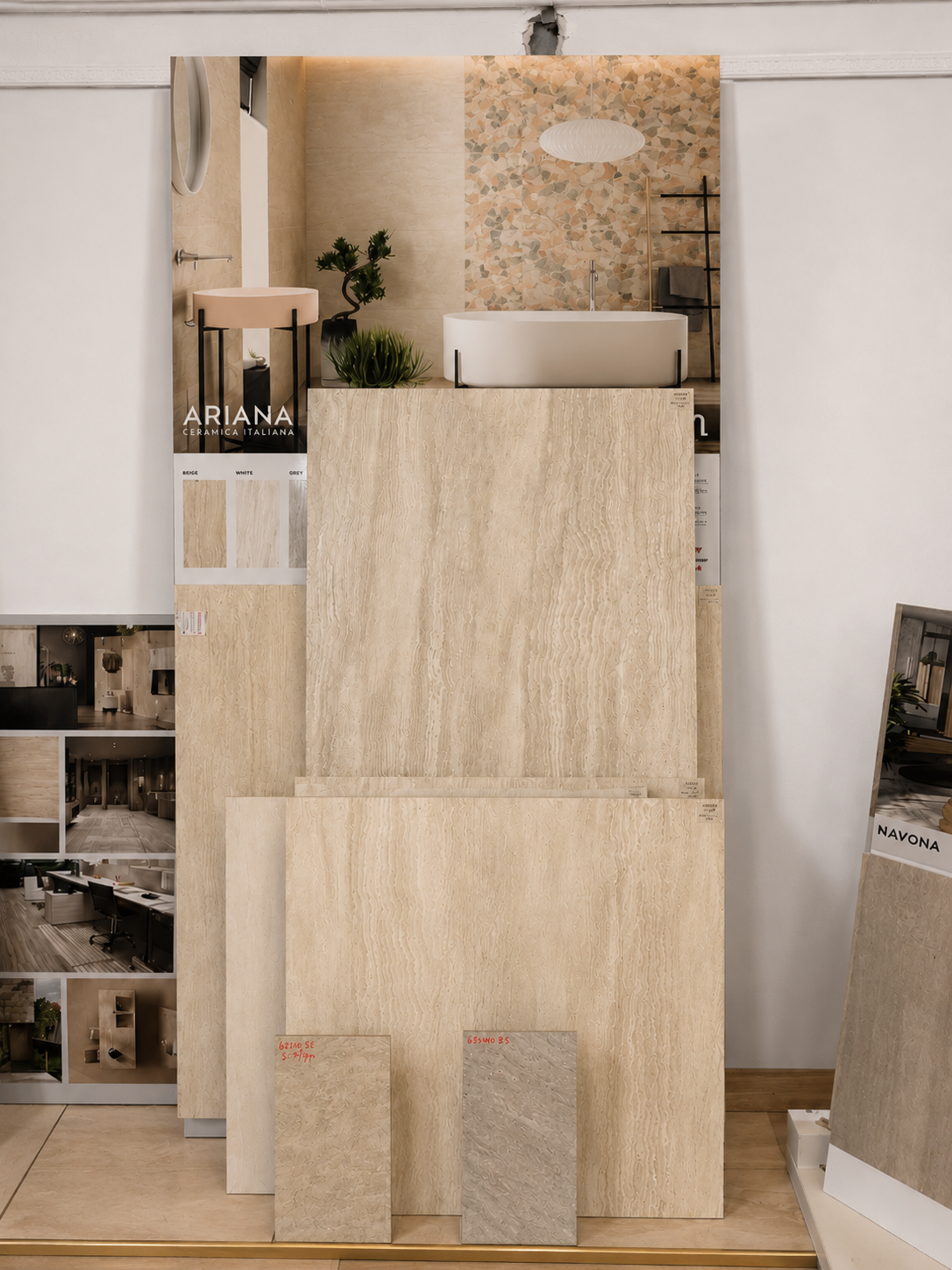Campioni di pietra e piastrelle beige impilati, esposti in uno showroom contro una parete bianca.