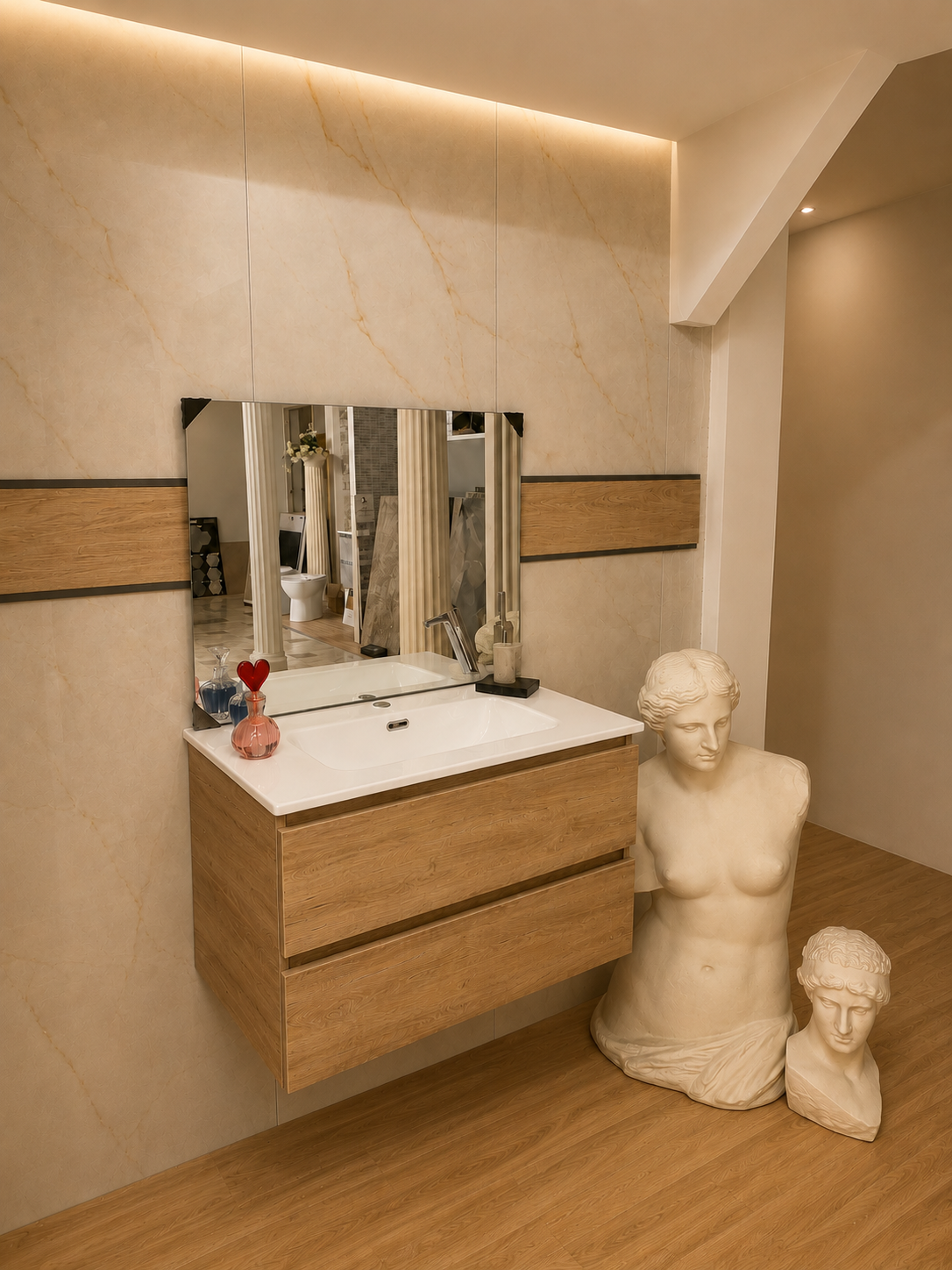Mobile bagno moderno con specchio, cassetti in legno, piano bianco e due sculture a busto in una stanza beige.