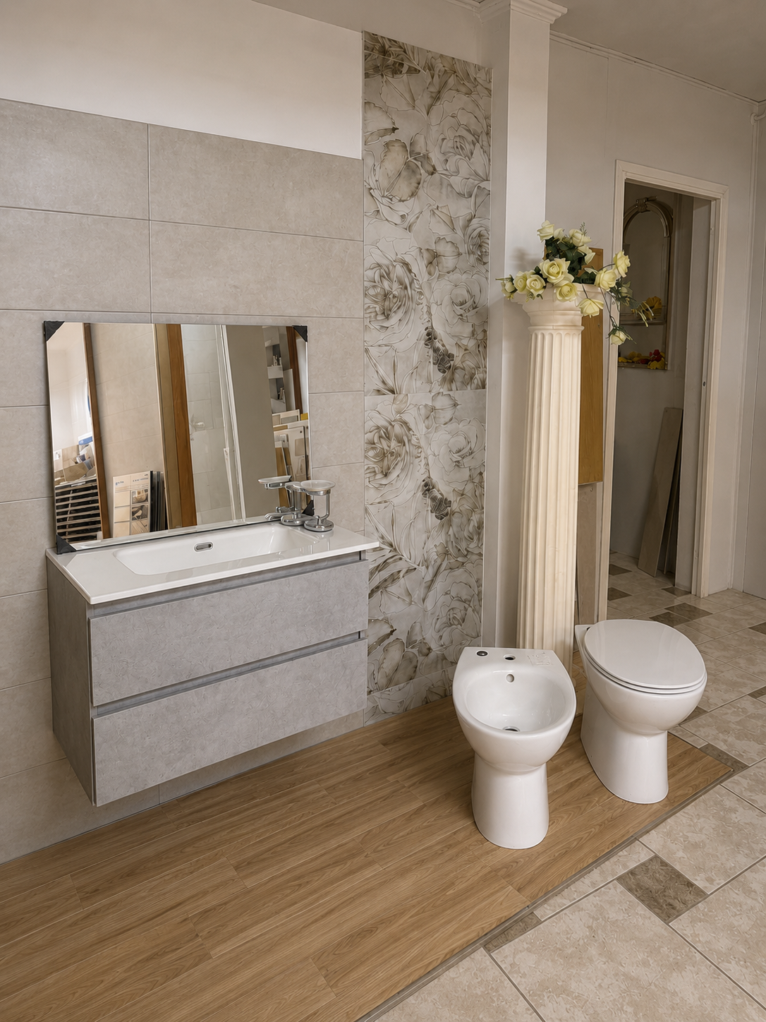 Bagno moderno con mobile lavabo sospeso, specchio, piastrelle decorative a motivi floreali e due WC bianchi su pavimento effetto legno.