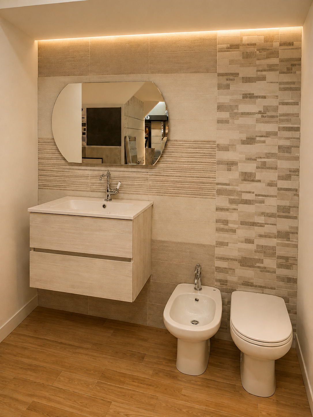 Bagno moderno color beige con mobile sospeso, specchio rotondo, WC, bidet e pavimento effetto legno.